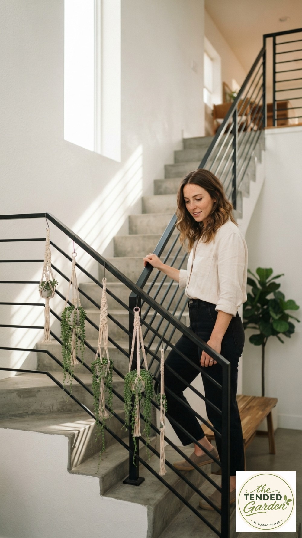 Woman beside a modern black stair railing plant hanger holding macrame slings with string-of-pearls succulents